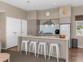 A kitchen with a cooking area and refrigerator at Mangawhai Heads Holiday Home in Mangawhai