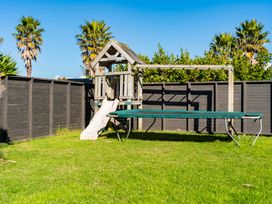 A playhouse with a slide and a trampoline at Mangawhai Heads Holiday Home in Mangawhai