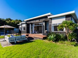 An outdoor area with a deck, furniture, and a grill at Mangawhai Heads Holiday Home in Mangawhai