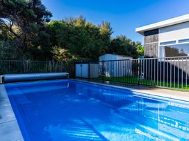 An outdoor area with a swimming pool and a shed at Mangawhai Heads Holiday Home in Mangawhai