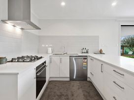 A kitchen with sink, stove, dishwasher and cabinets at Reporoa Holiday Home in Reporoa