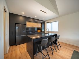 A kitchen with a refrigerator, island, and bar stools at Te anau Holiday home in Te Anau