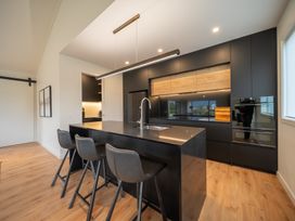 A kitchen with a black island and bar stools at Te anau Holiday home in Te Anau