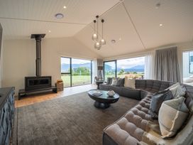 A living room with a sofa, coffee table, and wood stove at Te anau Holiday home in Te Anau