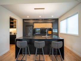 A kitchen with an island and bar stools at Te anau Holiday home in Te Anau