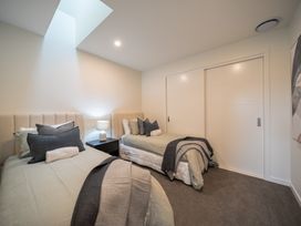 A bedroom with two beds and a bedside table at Te anau Holiday home in Te Anau
