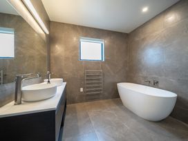 A bathroom with a bathtub and sinks at Te anau Holiday home in Te Anau