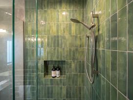 A shower with green tiles and bottles at Te anau Holiday home in Te Anau