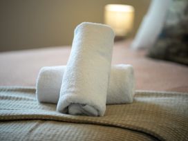 Two rolled towels on a bed at Te anau Holiday home in Te Anau
