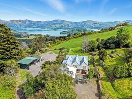 A house with a garage and garden overlooking a lake and mountains at Akaroa Holiday Home