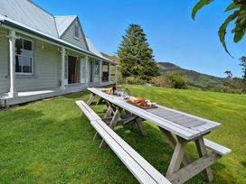 A picnic table with benches outside a house at Akaroa Holiday Home