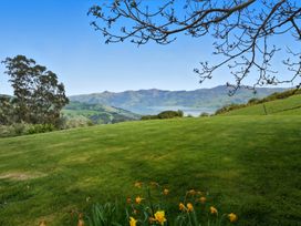A landscape with mountains and a lake surrounded by grass and trees at Akaroa Holiday Home
