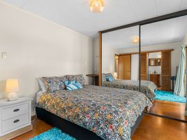 A bedroom featuring a bed and side table at Mangawhai Heads in Mangawhai