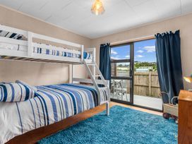 A bedroom with a bunk bed and a deck access at Mangawhai Heads in Mangawhai