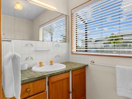 A bathroom with sink and mirror at Mangawhai Heads in Mangawhai