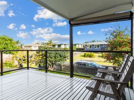 A deck with a wooden chair and view of the neighborhood at Mangawhai Heads in Mangawhai