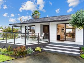 A house with a deck and seating area at Mangawhai Heads in Mangawhai