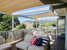 An outdoor deck with seating and a table at Whiritoa Holiday House in Whiritoa