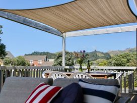 An outdoor seating area with a table, chairs, and a view at Whiritoa Holiday House in Whiritoa