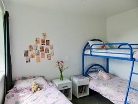 A bedroom with a bunk bed and single bed at Whiritoa Holiday House in Whiritoa