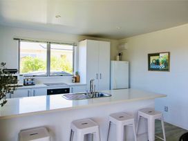 A kitchen with a sink and refrigerator at Whiritoa Holiday House in Whiritoa