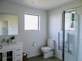 A bathroom with a sink, toilet, and shower at Whiritoa Holiday House Whiritoa