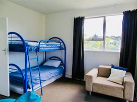 A bedroom with a bunk bed and a sofa at Whiritoa Holiday House in Whiritoa