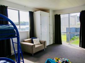 A bedroom with a bunk bed and a sofa at Whiritoa Holiday House in Whiritoa