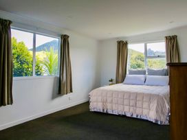 A bedroom with a bed and windows facing mountains at Whiritoa Holiday House in Whiritoa