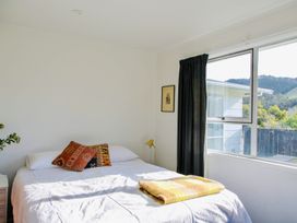 A bedroom with a bed and lamp at Whiritoa Holiday House in Whiritoa