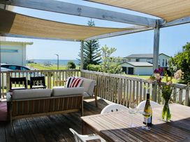A deck with outdoor furniture and a table at Whiritoa Holiday House Whiritoa
