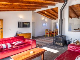 A living room with a sofa, coffee table, and dining area at Railside Chalet - Raurimu Holiday Home National Park
