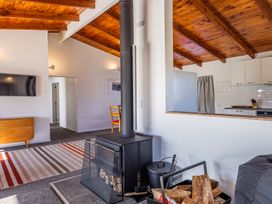 A living room with a stove and television at Railside Chalet - Raurimu Holiday Home National Park