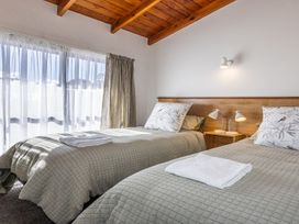 A bedroom with two beds and natural light from a window at Railside Chalet - Raurimu Holiday Home, National Park