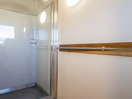 A shower with a glass door and a wooden grab bar at Railside Chalet - Raurimu Holiday Home National Park