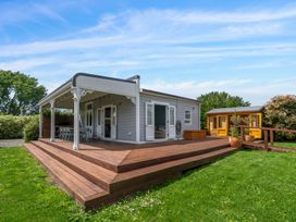 A house with a deck and garden area featuring seating and a yellow shed at location