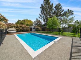 A swimming pool with surrounding decking and garden at a residential property