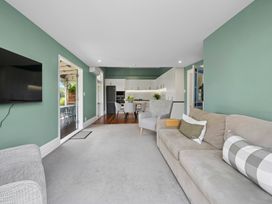 A living room with a sofa and television leading to a kitchen at the property