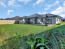 A house with a deck and lawn at Serendipity at One Tree Point - Whang?rei Holiday Home