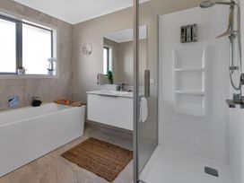 A bathroom with bathtub and shower at Serendipity at One Tree Point - Whang?rei Holiday Home