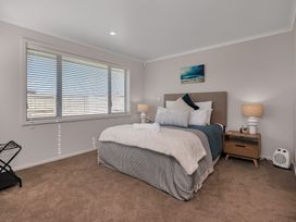 A bedroom with a bed and nightstand at Serendipity at One Tree Point - Whang?rei Holiday Home