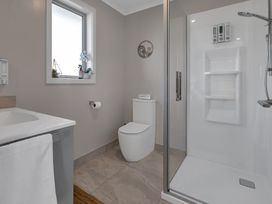 A bathroom with a shower and toilet at Serendipity at One Tree Point - Whang?rei Holiday Home