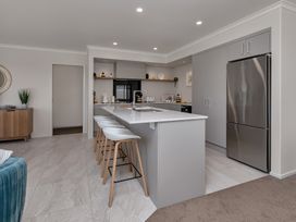 A kitchen with bar stools and appliances at Serendipity at One Tree Point - Whang?rei Holiday Home