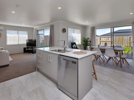 A kitchen and dining area with a television and sofa at Serendipity at One Tree Point - Whang?rei Holiday Home