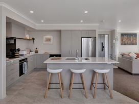 A kitchen with bar stools and modern appliances at Serendipity at One Tree Point - Whang?rei Holiday Home