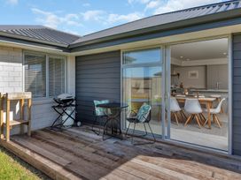 An outdoor patio with a table and chairs leading to a kitchen at Serendipity at One Tree Point - Whang?rei Holiday Home