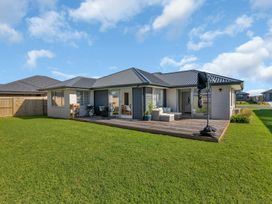 A house with a deck and furniture in a garden at Serendipity at One Tree Point - Whang?rei Holiday Home