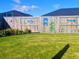 A garden with a fence and decorative art at Serendipity - One Tree Point Holiday Home One Tree Point