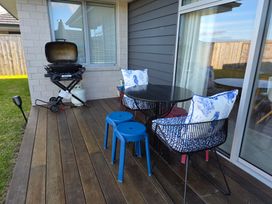 An outdoor seating area with a grill table and chairs at Serendipity - One Tree Point Holiday Home One Tree Point