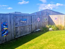 A garden with grass and painted wooden fence at Serendipity - One Tree Point Holiday Home One Tree Point